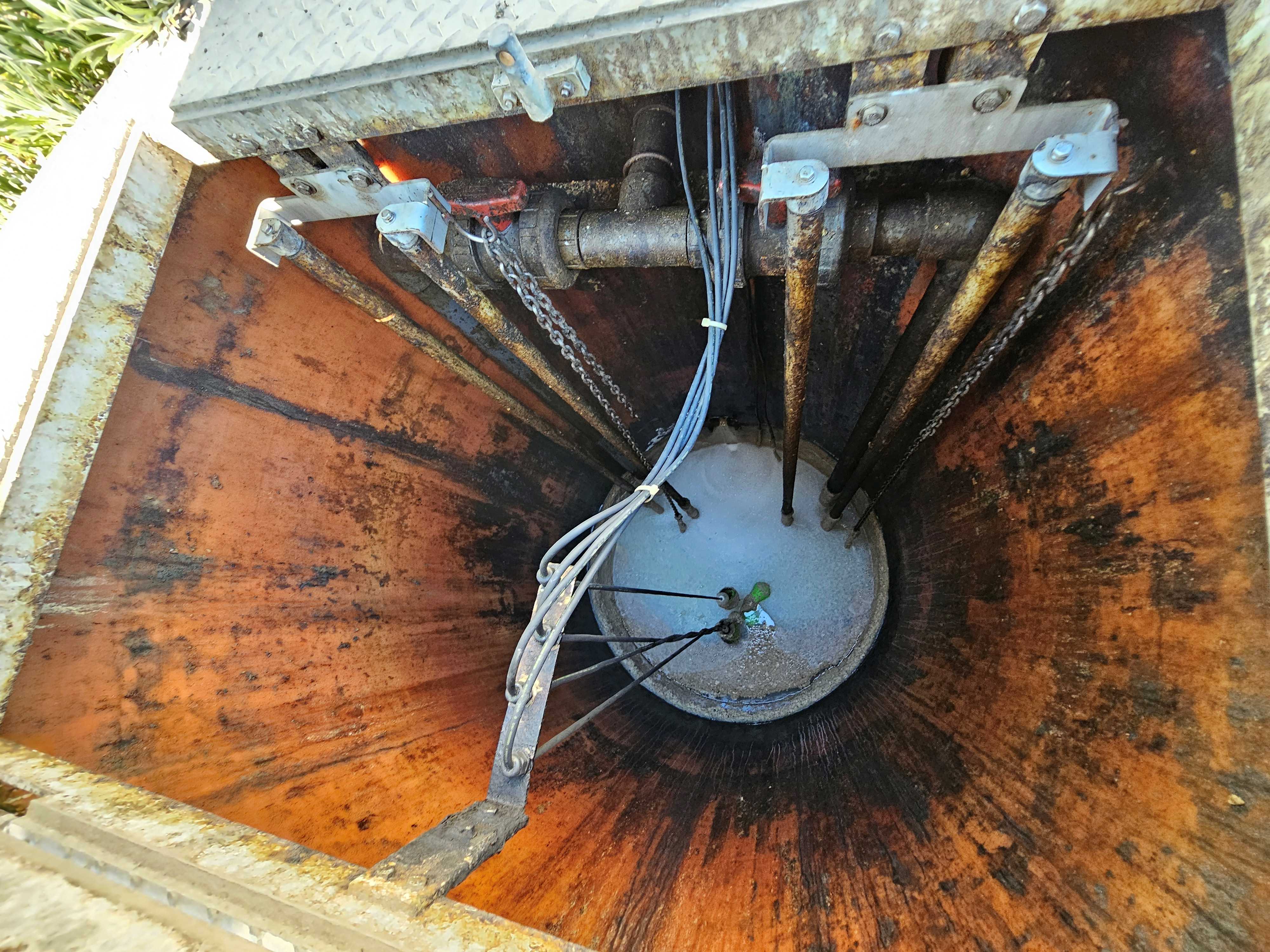 Professional inspection of lift station wet well interior showing pump system and control components